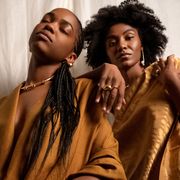 two black women in brown clothing model gold fine jewelry from the brand khiry