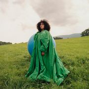 tracee ellis ross poses in green ensemble with large blue balloon in the background